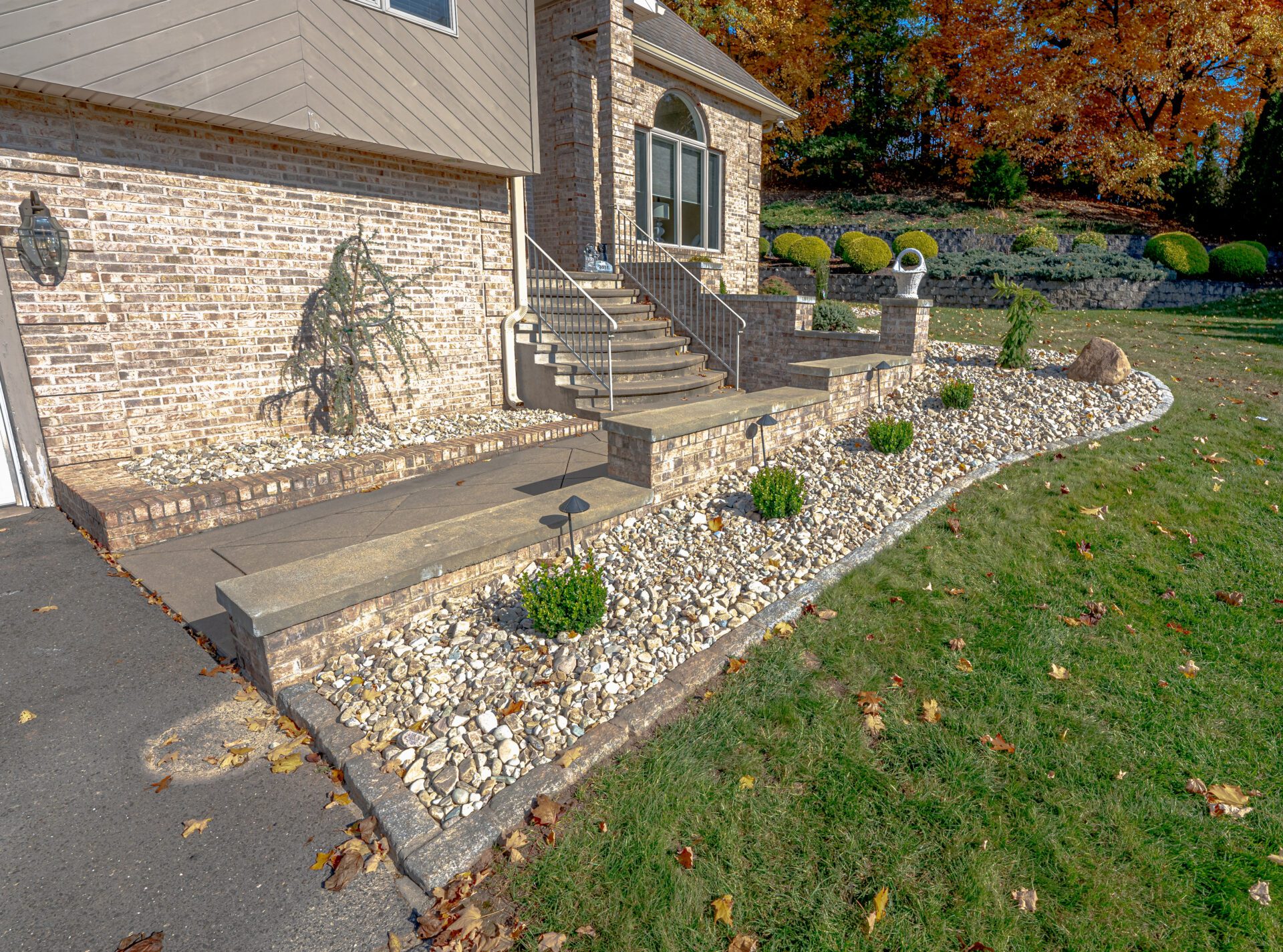 Stone-bordered landscaping with shrubbery and brick steps leading to a home entrance.